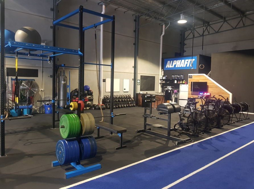 A gym with a blue track and a bunch of weights on the floor.