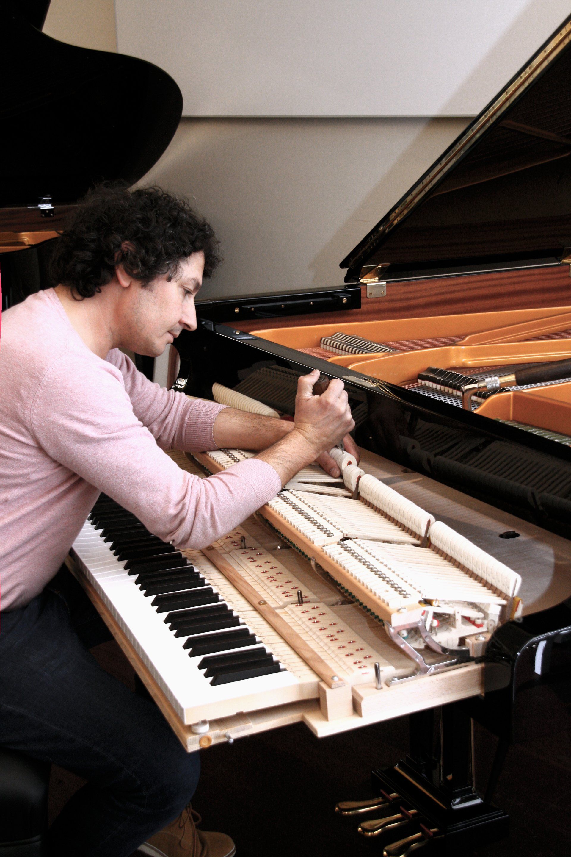 Pianostemmer Popov stemt een C. Bechstein vleugel met de toetsen zichtbaar en de klep open.