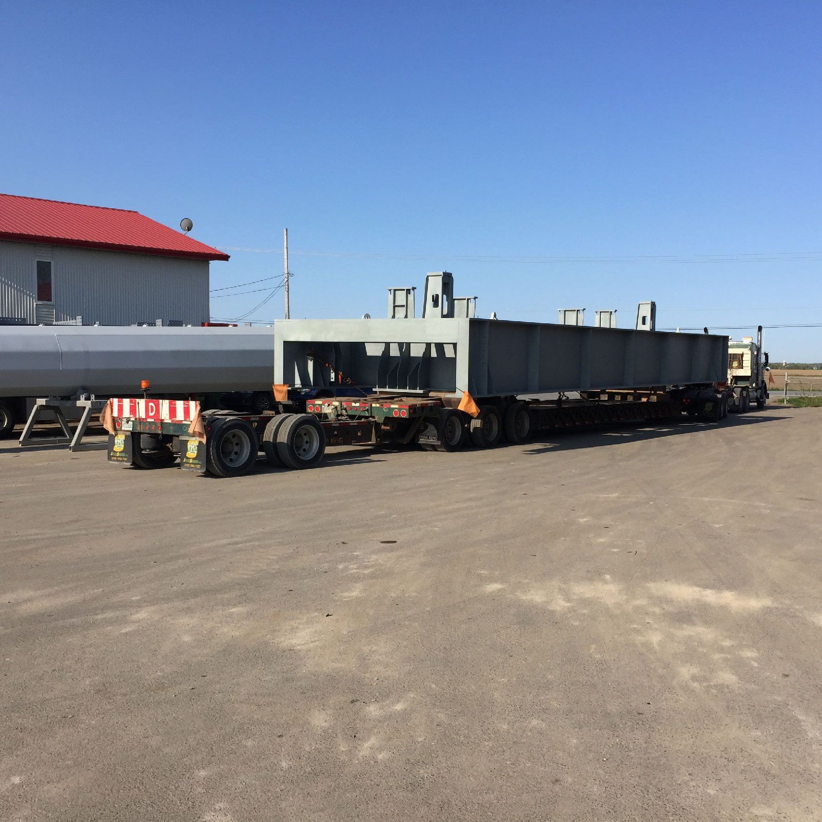 Un camion transporte un gros morceau de métal sur un parking