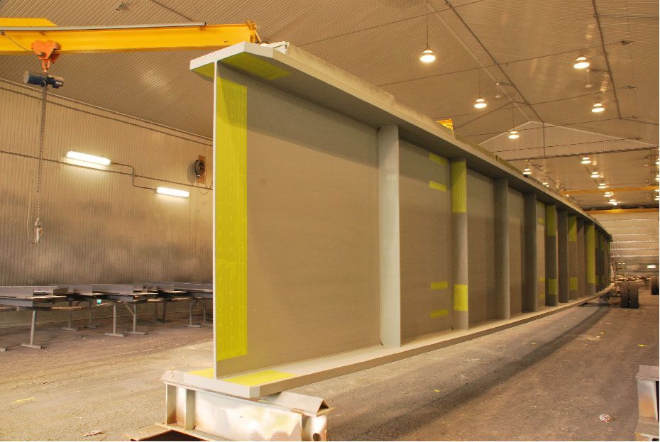 Une grande structure métallique est en cours de peinture dans une usine