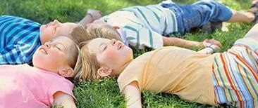 Children lying on the grass — Early Learning Center in Tiverton, RI Children lying on the grass — Early Learning Center in Tiverton, RI