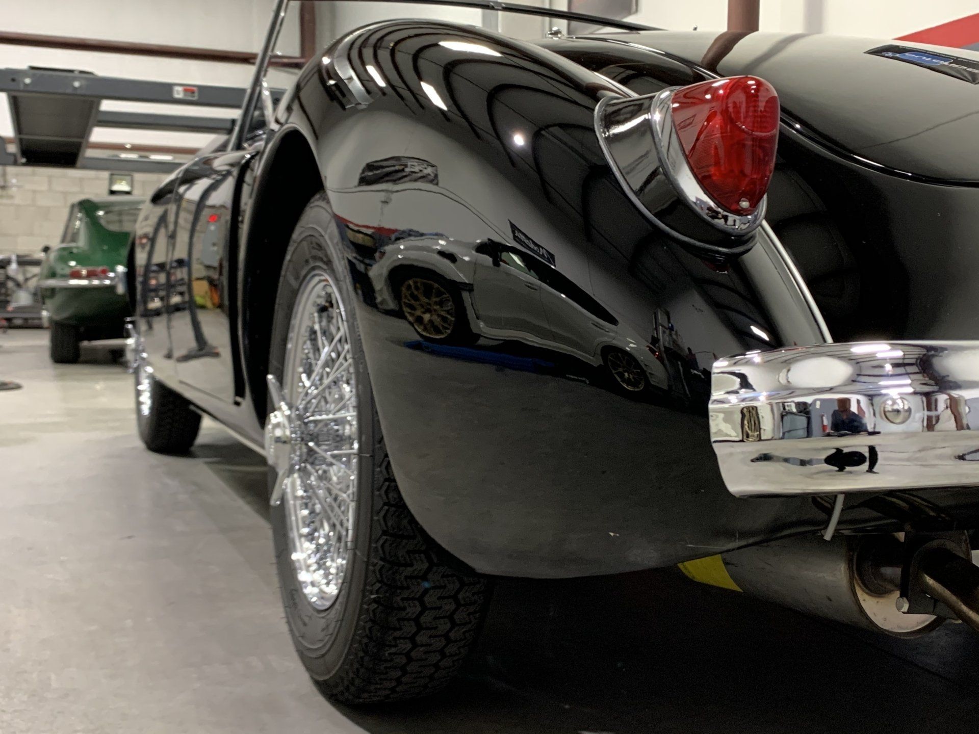 A black car with chrome wheels is parked in a garage
