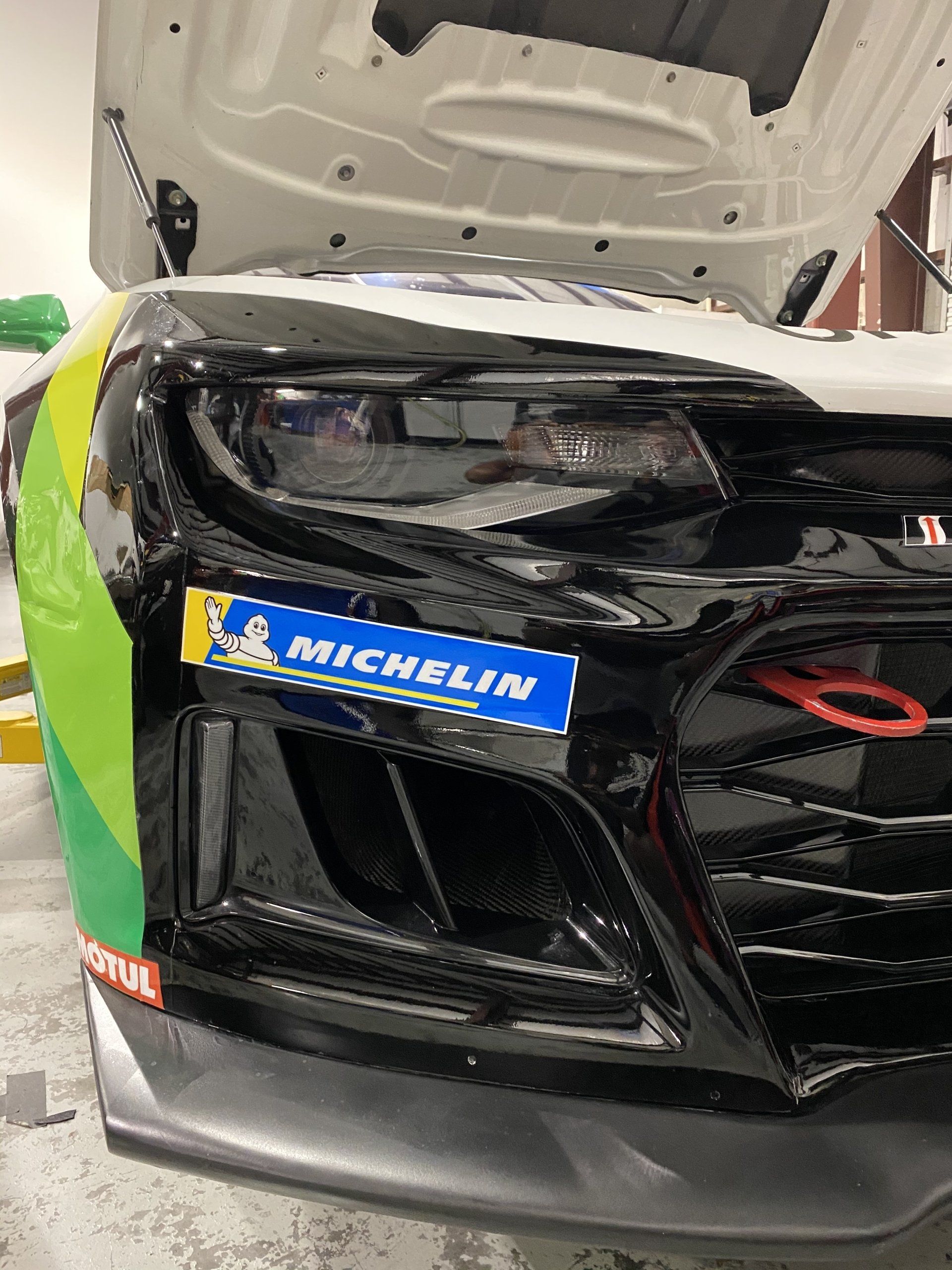 A black car with a michelin sticker on the front bumper.