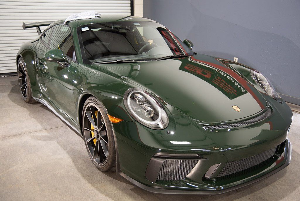 A green porsche 911 gt3 rs is parked in a garage.