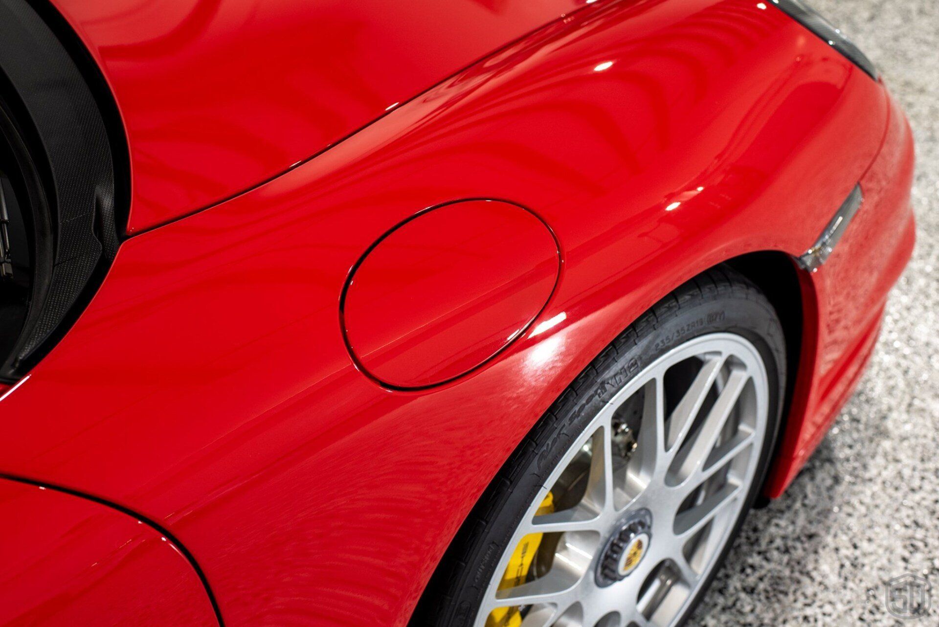 A close up of a red sports car with a fuel cap on the side.