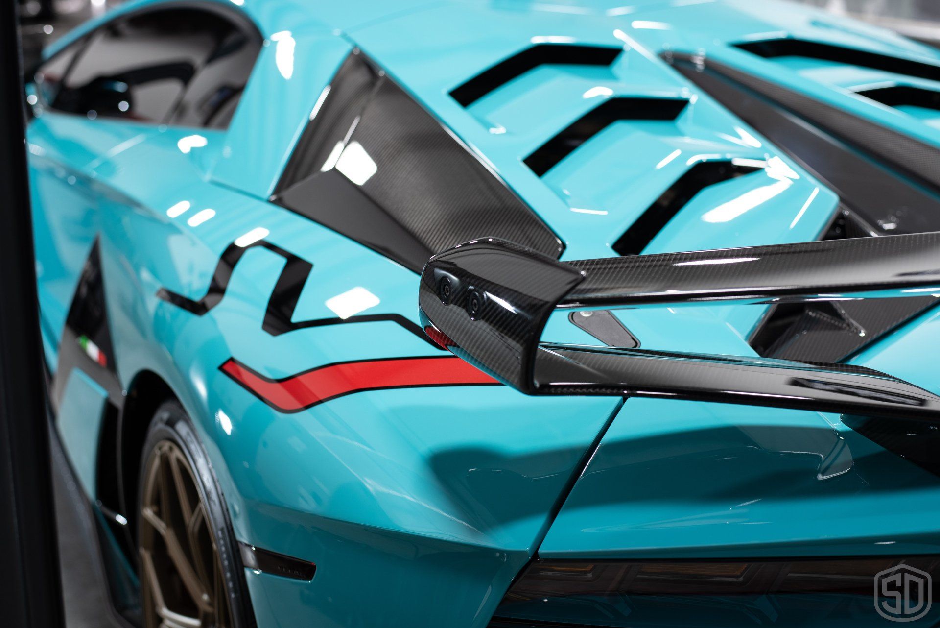 A close up of the rear end of a blue lamborghini aventador