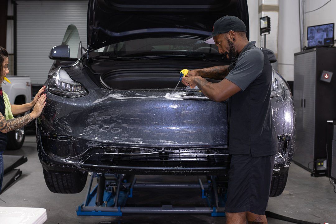 A man is working on a tesla model 3 in a garage.