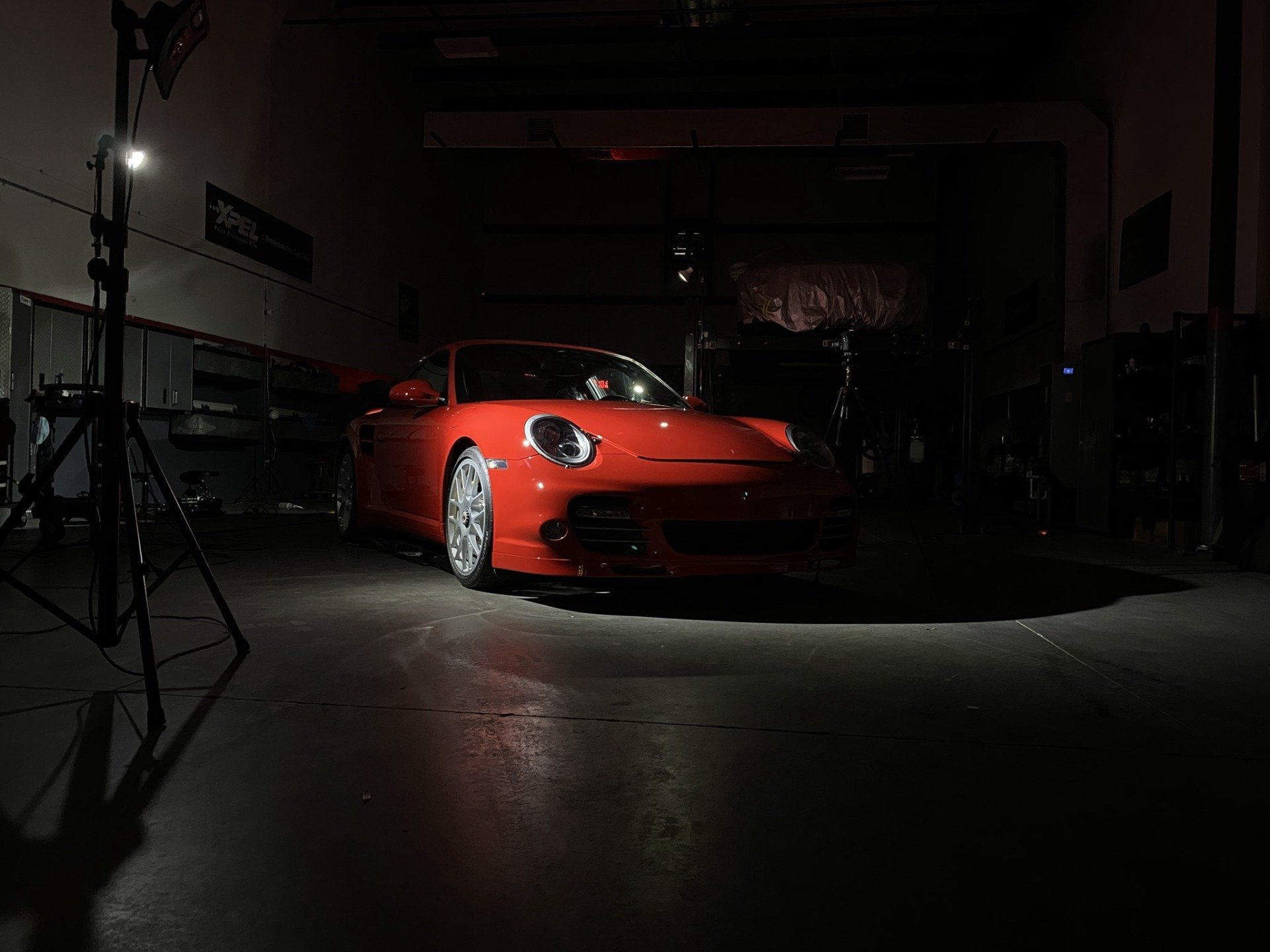 A red porsche 911 is parked in a dark garage.