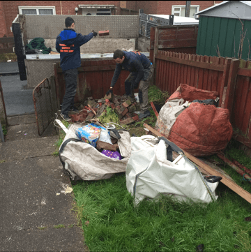 An image of a cluttered garden with a man working to clear it