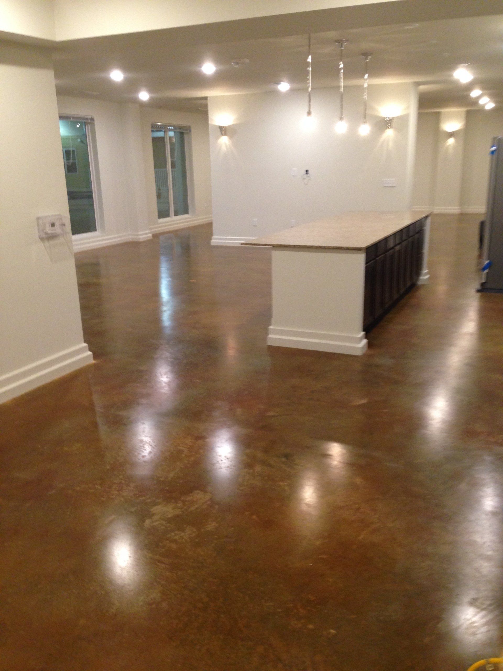 Spacious room with brown, polished concrete floor, white walls, and a kitchen island.