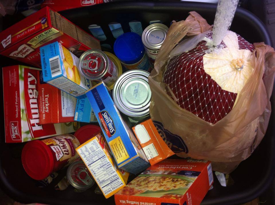 Basket of groceries, including a turkey, canned goods, and boxed side dishes.