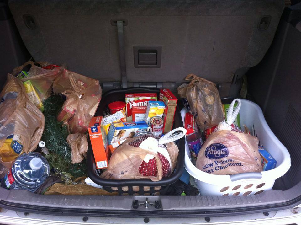 Trunk of a car filled with groceries: bags, baskets, and a turkey.