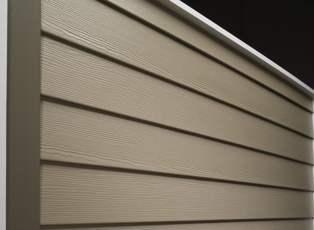 Close-up of beige vinyl siding on a house exterior with horizontal panels and trim.