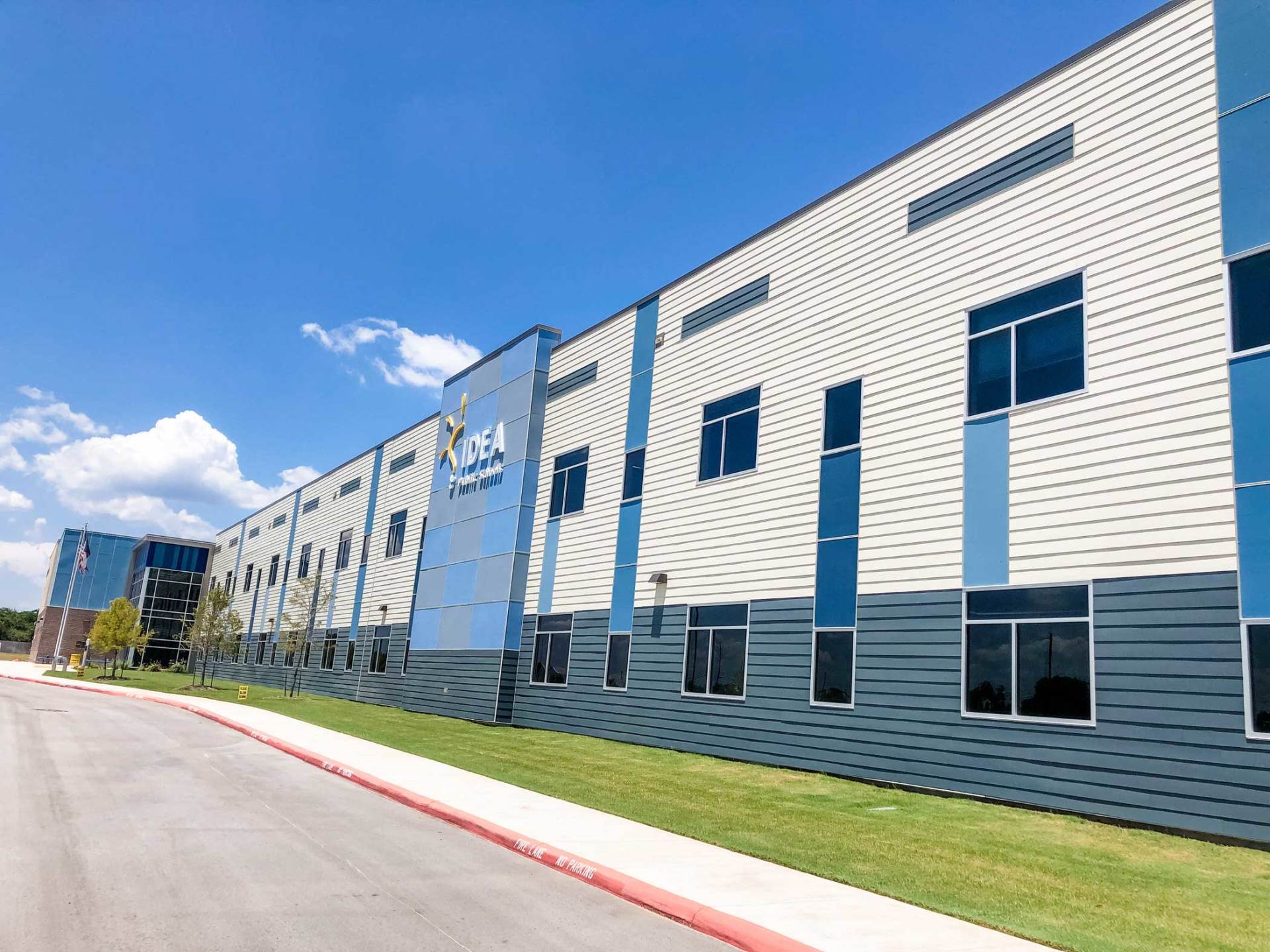 Modern gray-and-blue industrial building beside a road under a clear blue sky