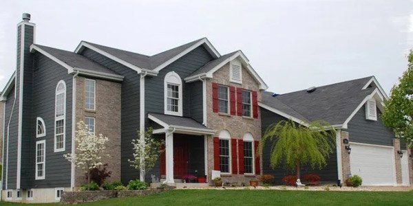 Suburban brick and gray house with red shutters, a front porch, and an attached garage