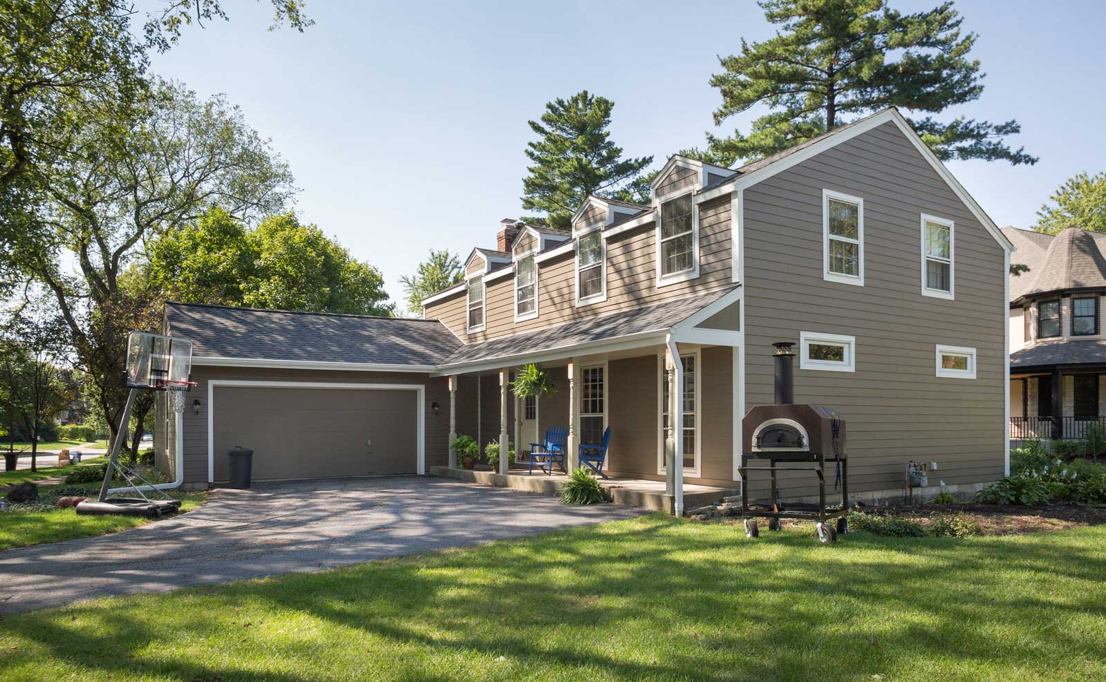 Suburban two-story house with garage, porch, and green lawn on a sunny day