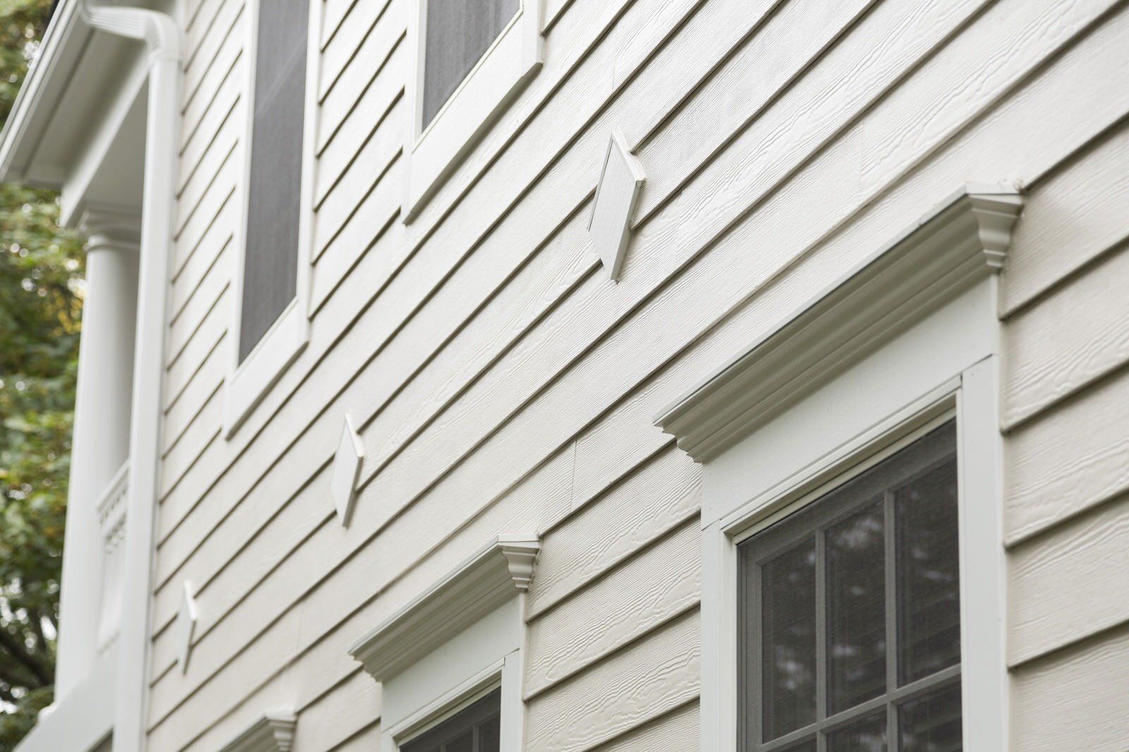 White house siding with windows and small exterior vents viewed from below