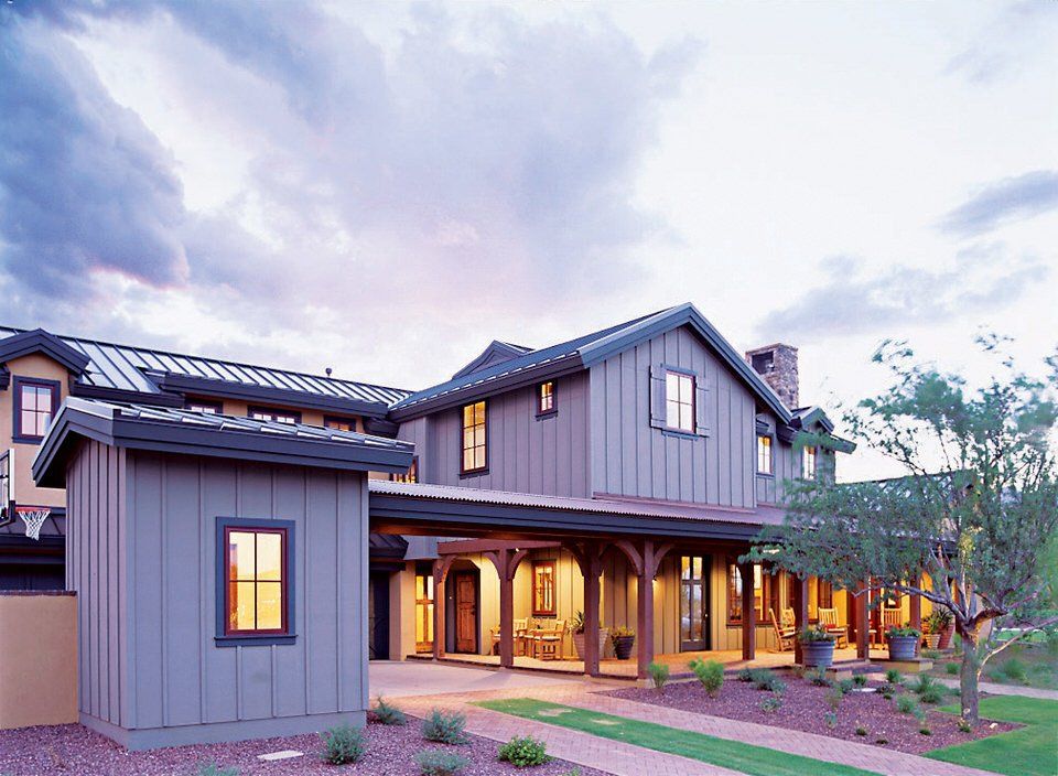 Modern gray two-story house with warm porch lights at dusk and a landscaped front yard