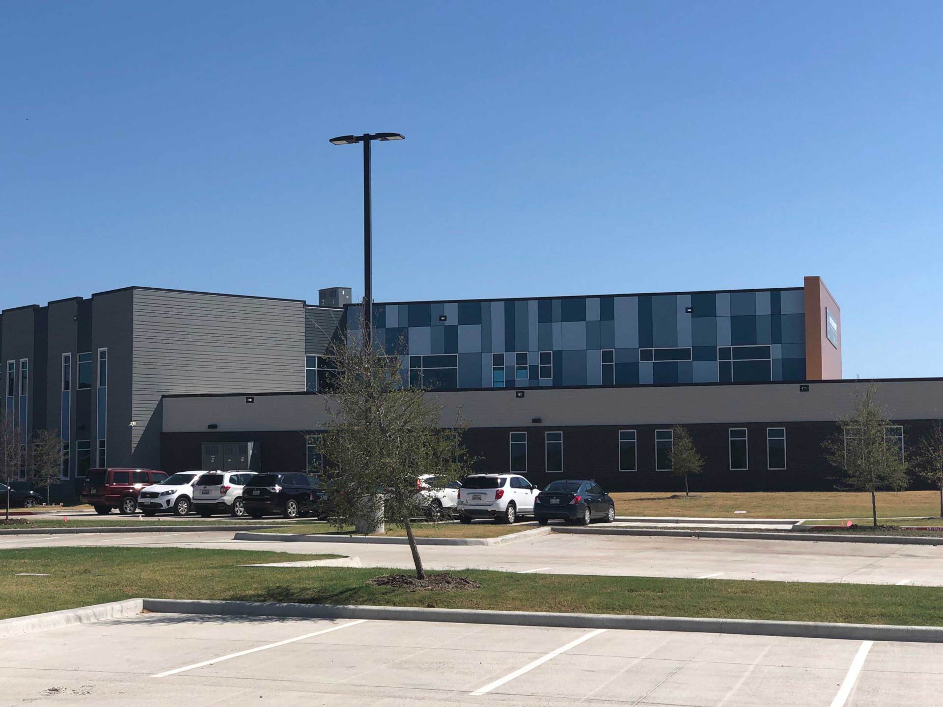 Modern building exterior with parked cars under a clear blue sky