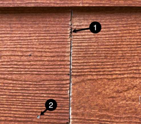 Close-up of brown wooden siding with a vertical crack and two numbered markers pointing to damage.
