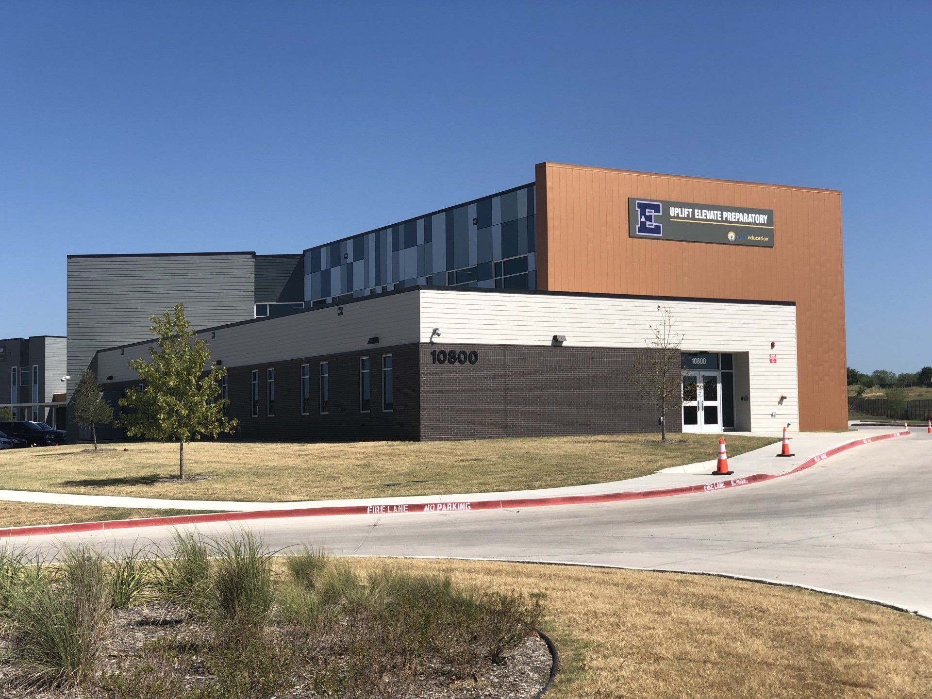 Modern commercial building with wood and white siding, large windows, and a sign above the entrance