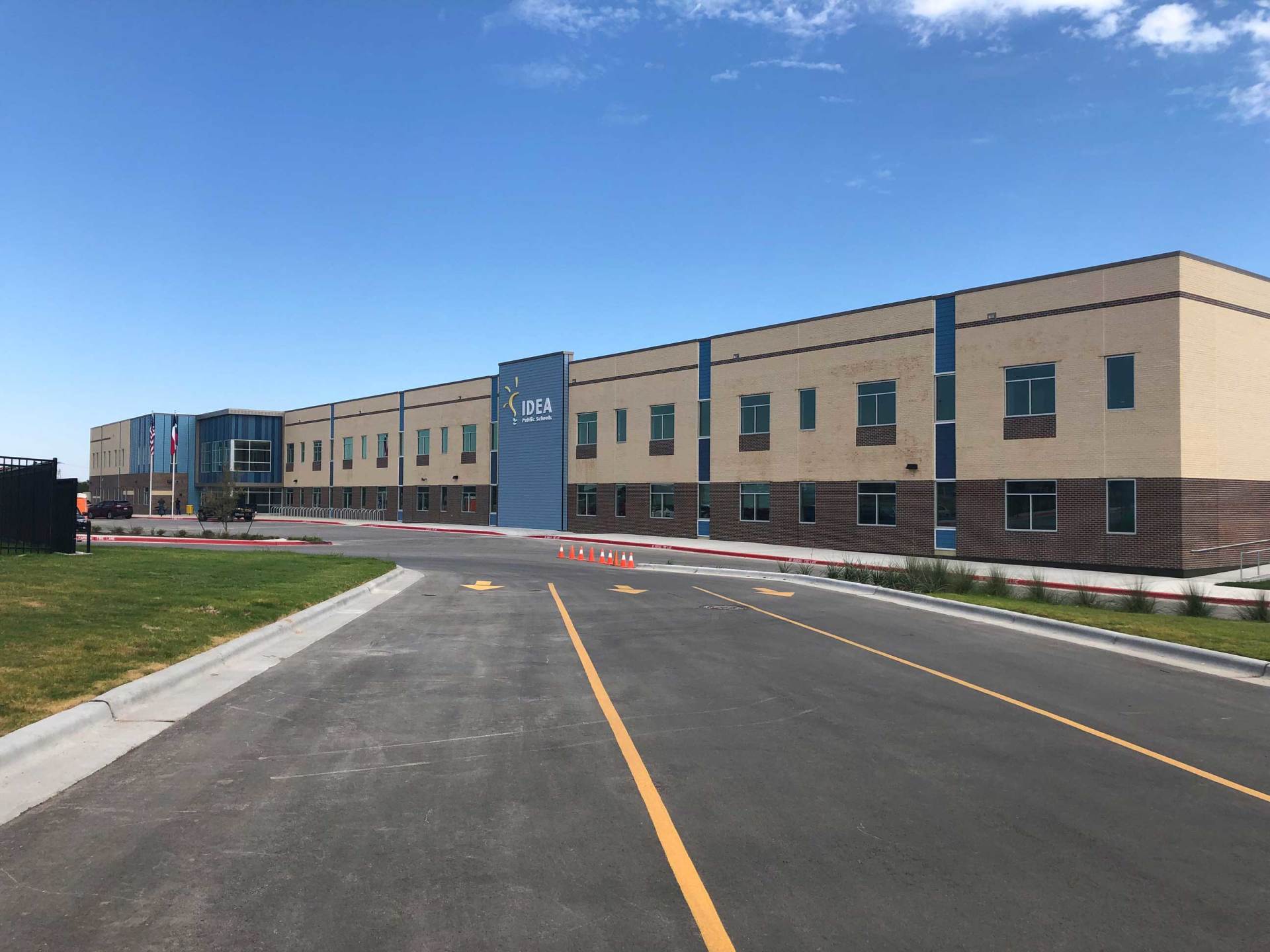 New tan building with blue accents beside a paved road under a clear blue sky