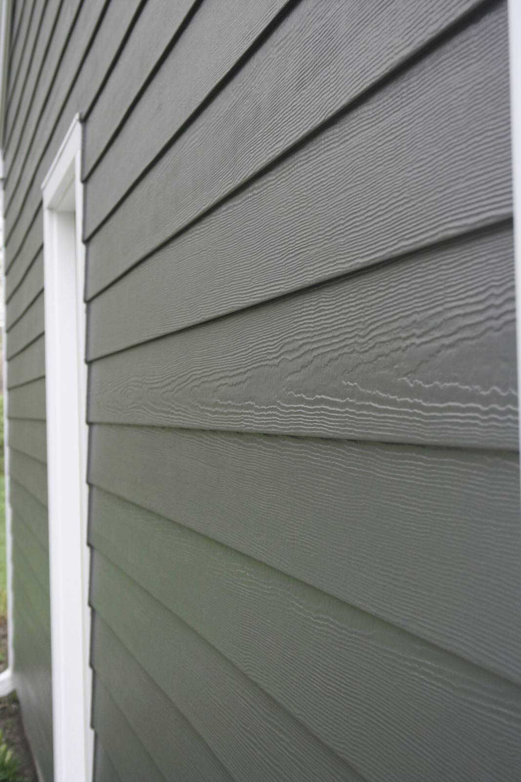Close-up of gray house siding with white trim along an exterior wall