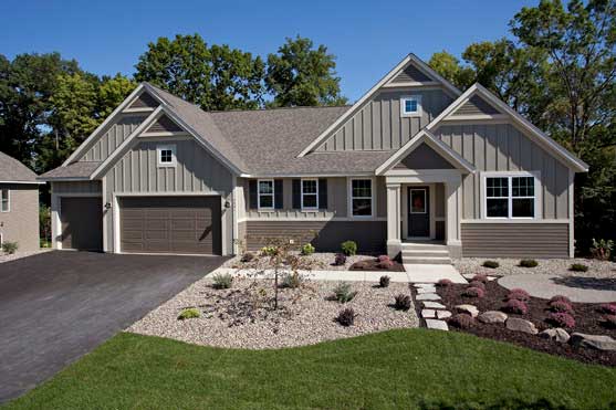 Modern beige suburban house with gray roof, attached garage, and landscaped front yard
