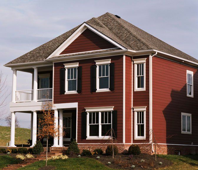 Red two-story house with white trim and a small front porch on a grassy lot