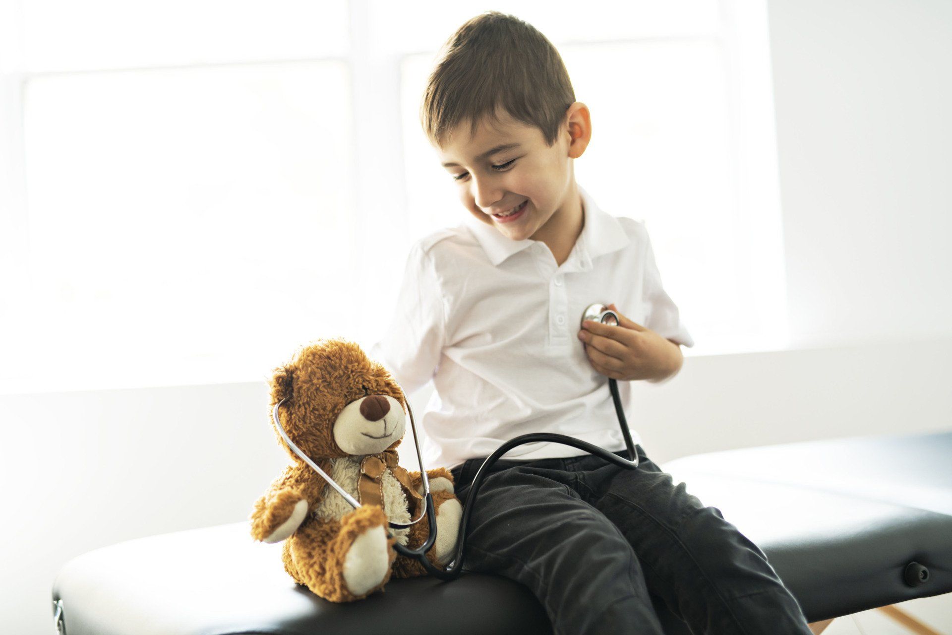 Young boy with stethoscope and teddy bear