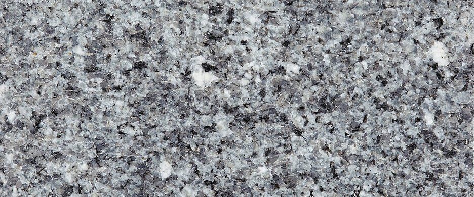 A close-up texture of gray granite stone featuring a speckled pattern of black, white, and gray mineral grains.