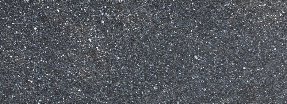 A close-up texture of dark grey, speckled stone or quartz countertop material.