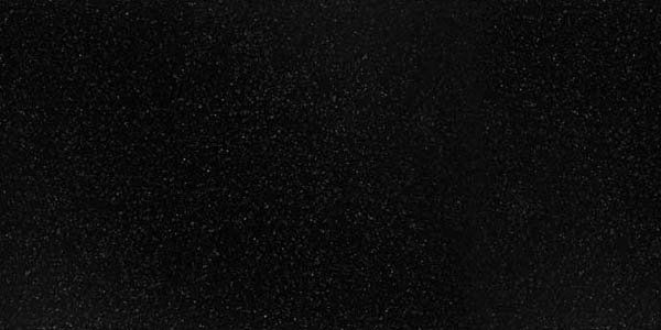 A close-up of a solid black, fine-grained surface texture with subtle, light-colored speckling throughout.