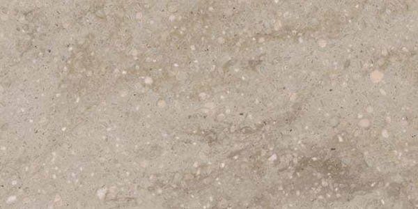A close-up view of a matte, light-gray textured surface with scattered white and beige specks resembling stone or concrete.