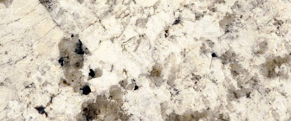 Close-up of white granite countertop featuring gray, tan, and black mineral flecks and veining.