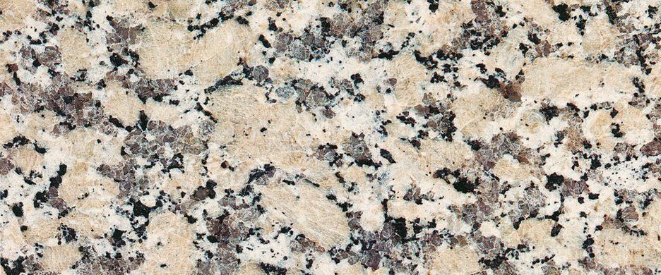 A close-up view of granite with speckled patterns in shades of beige, gray, white, and black.