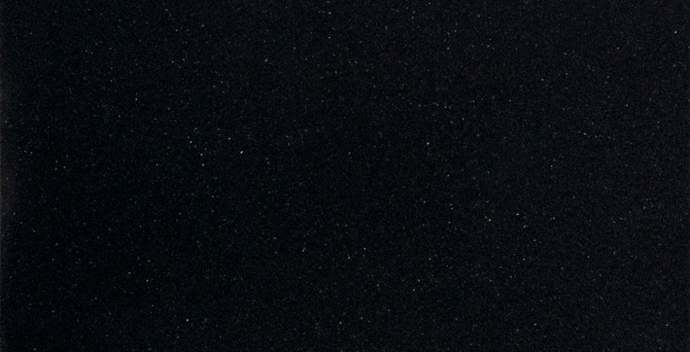 A textured black background with fine, scattered silver-colored specks.