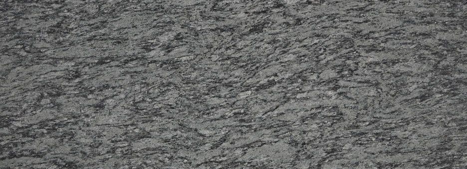 A close-up, top-down view of rough, grey, freshly tilled soil with small clods and textured patches.