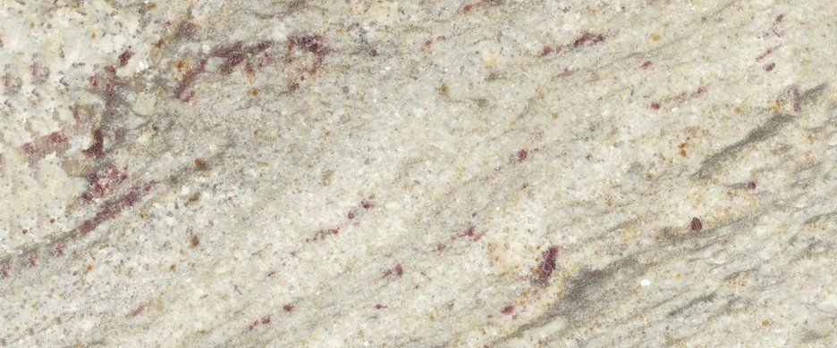 Close-up of polished granite slab with a cream, grey, and white background, featuring streaks of dark red and brown.
