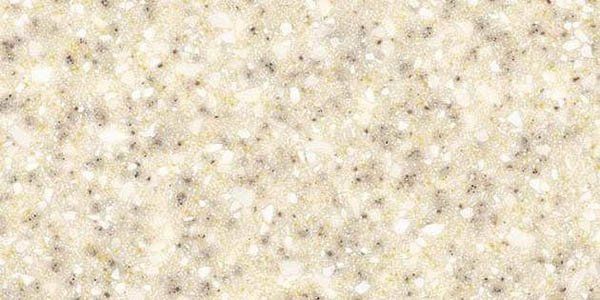 A close-up texture of beige granite or solid surface material with speckled white and grey flecks.