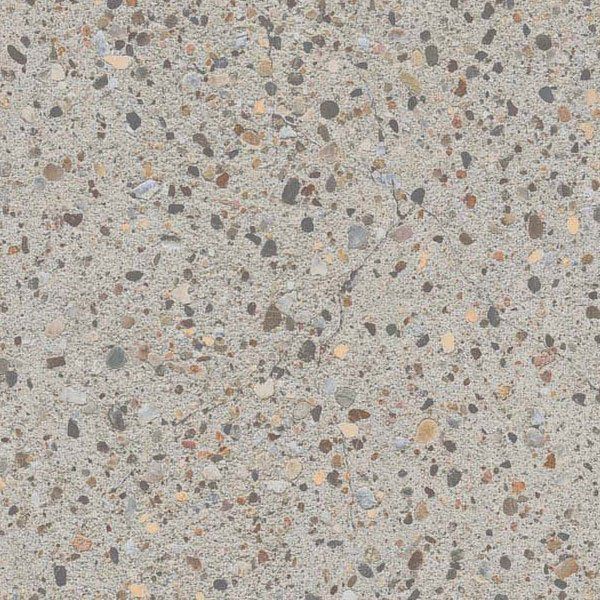A close-up of light gray concrete with an exposed aggregate finish, showing a mix of small, multicolored pebbles.