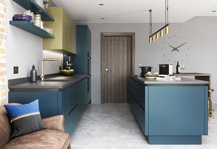 A modern kitchen with deep blue cabinets, light wood upper cupboards, a central island, and a dark leather armchair.