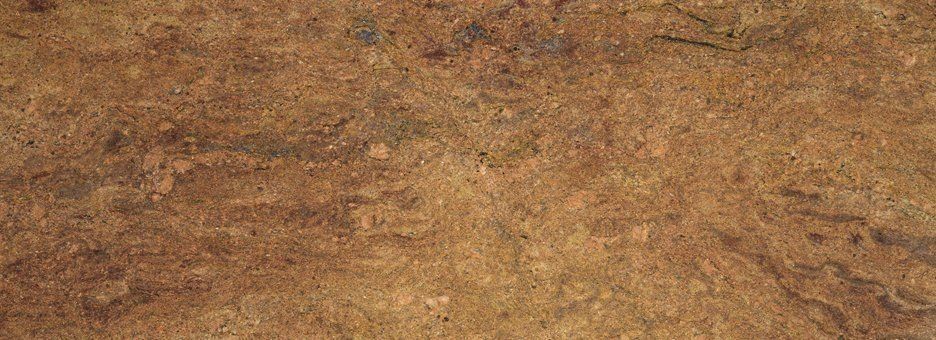 A close-up shot of a textured, mottled surface in shades of brown, tan, and dark gold, resembling polished granite.
