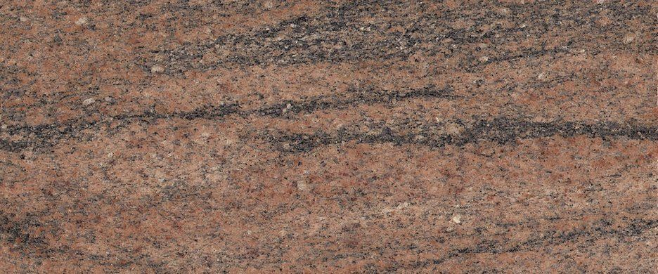 A close-up view of polished granite stone with a mottled, warm-toned texture featuring brown and black wavy patterns.