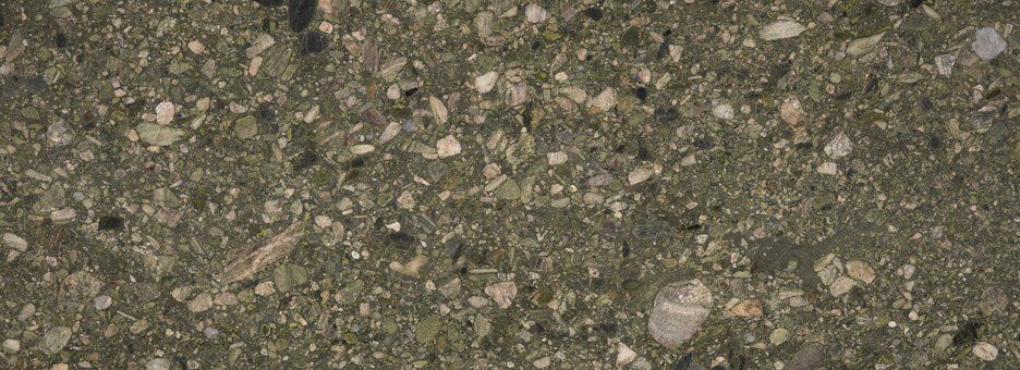 Close-up of a dark olive-green concrete surface with speckled, light-colored gravel aggregate.