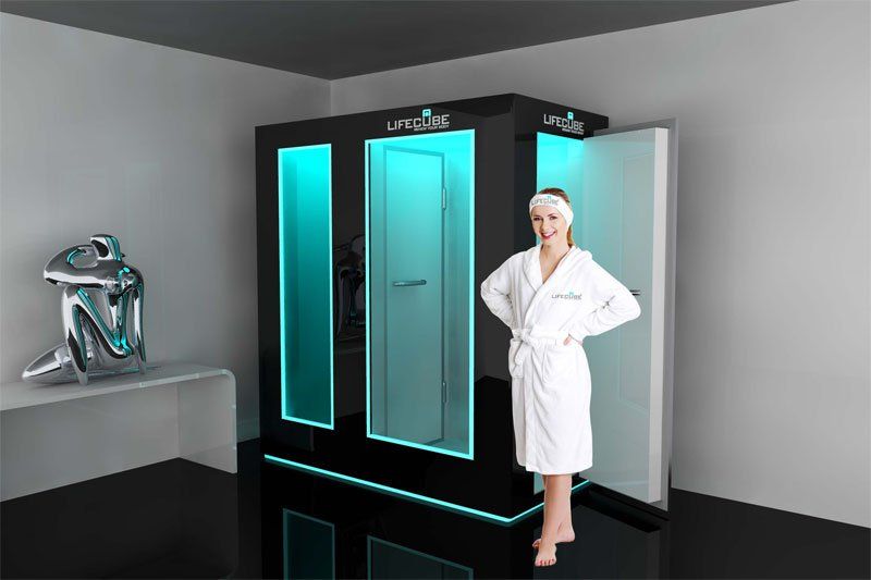 Beyaz cübbeli kadın, mavi ışıklı bir kriyoterapi odasının yanında duruyor. Modern, minimalist bir oda.