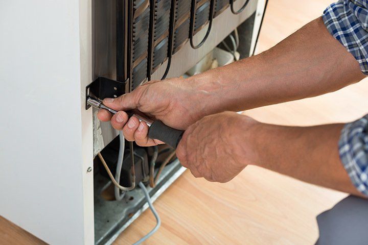 Serviceman Working On Fridge at Home — Kansas City, MO — At Your Service Appliance Repair