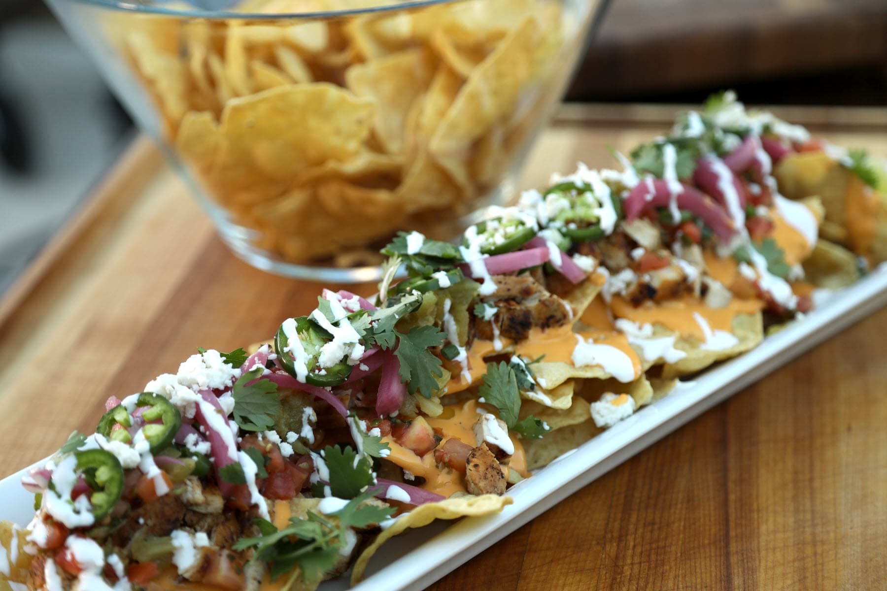 BBQ Chicken Nachos with bowl of tortilla chips in background