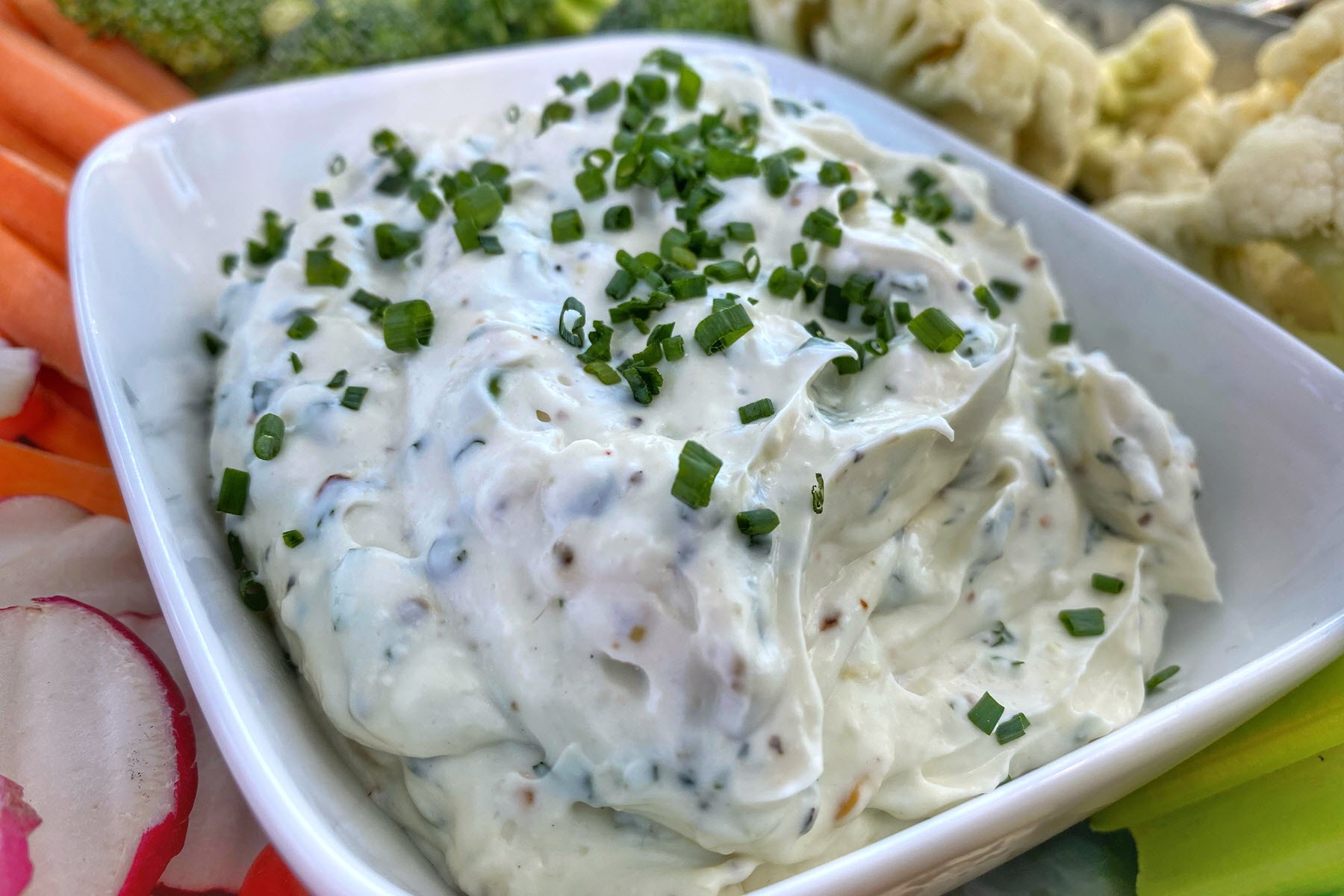 Vegetable dip in a bowl garnished with chives