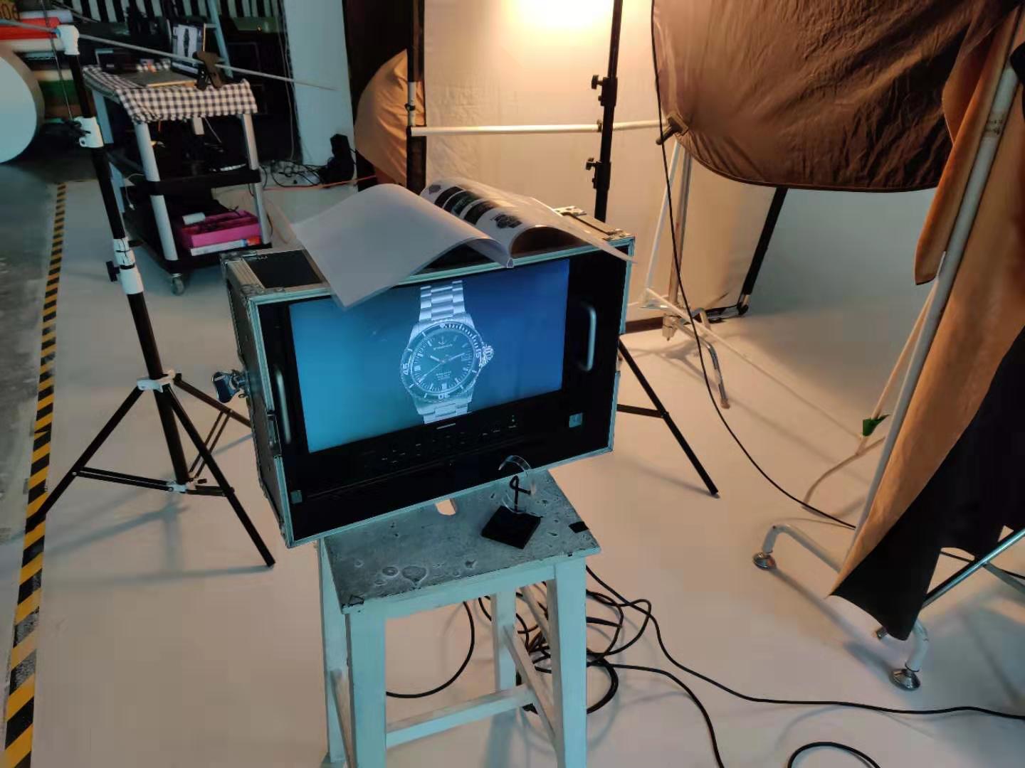 A watch is displayed on a computer screen in a photo studio